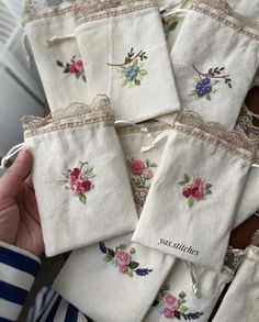 several pieces of cloth with embroidered flowers and lace on them are being held by a woman's hand