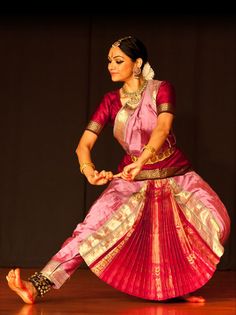 a woman in a pink and gold dress dancing