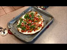 a pizza sitting on top of a metal pan covered in toppings next to a bottle opener