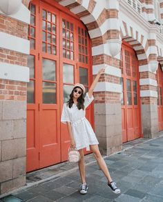 a woman standing in front of a red door with her hand up to the side