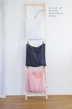 three shirts hanging on a clothes rack in front of a white wall with writing above it