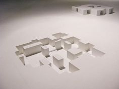 several white cubes are arranged in the shape of an abstract structure on a plain surface