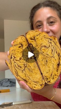 a woman holding up a large piece of bread