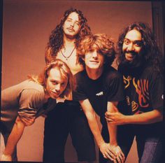 four people posing for the camera in front of a wall with an image of them