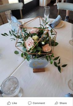 the table is set with white and pink flowers, greenery, and wine glasses