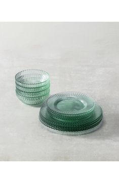 stack of green glass plates sitting on top of a white table next to each other