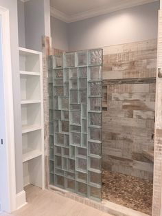 an empty bathroom with glass blocks on the shower wall and shelves in the back ground