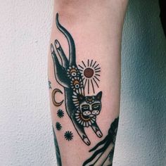 a black and white cat tattoo on the left arm, with sun in the background