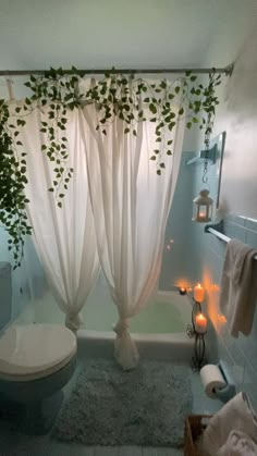 a bathroom with a toilet, shower curtain and candles in the bathtub next to it