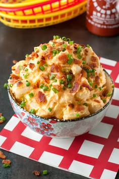 a bowl filled with potato salad on top of a red and white checkered table cloth