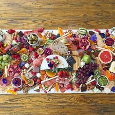 a large platter filled with lots of different types of cheeses and fruit on top of a wooden table