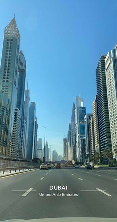 an empty street with tall buildings in the background and a sign that says dubai united arab emirates