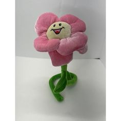 a stuffed flower with a smiling face on it's head and legs, sitting on a white surface