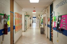 an empty hallway with posters on the walls and bulletins on the wall behind them