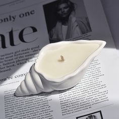 a candle that is sitting on top of a magazine with an article in the background