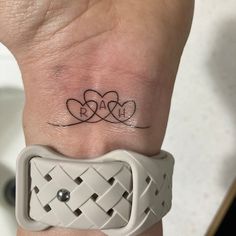 a wrist tattoo with two hearts on it