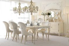 a dining room table with white chairs and chandelier