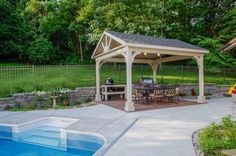 a backyard with a pool and gazebo surrounded by trees