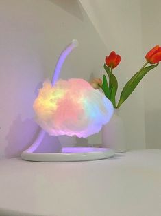 a white table topped with a vase filled with red tulips and a cloud