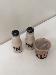 two plastic cups sitting next to each other on a white counter top, one with chocolate frosting and the other without icing