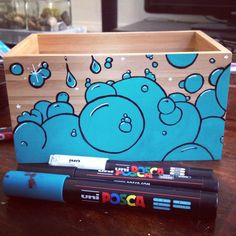 a wooden box sitting on top of a table next to a marker and pencil holder