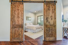 an open door leading to a bedroom with a large bed in the background and hardwood floors