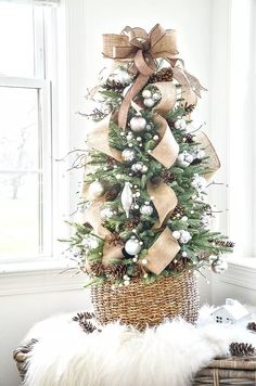 a small christmas tree in a wicker basket with burlap bows and ornaments