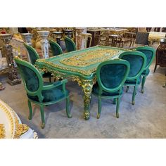 a table and chairs with green velvet upholstered on the top, surrounded by gold trimmings