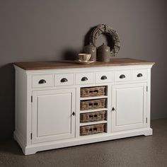 a white sideboard with drawers and baskets on top