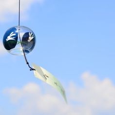 a wind chime hanging from the side of a blue sky with clouds in the background