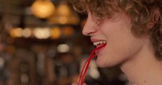 a close up of a person with curly hair and red lipstick on his lips smiling