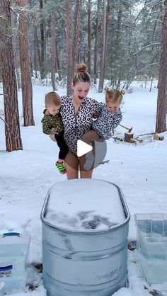 two young children are playing in the snow with an ice bucket and water jugs