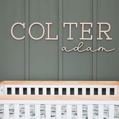 a baby crib in front of a wall with the name coller adam on it