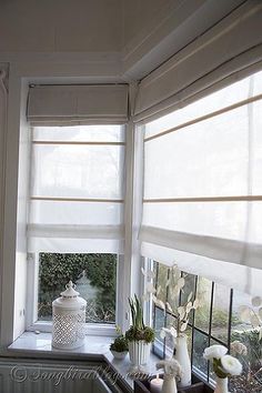 a kitchen window with white flowers and vases on the windowsill