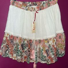 Raga Nwt Mini Skirt Love This It Has A Cream Too With Gold Strands Through The Material With A Floral Bottom. There Are Embellishments At The Fabric Split Line. Love! It Is The Gauze Material But Able Layered. Bohemian Short Mini Skirt For Spring, Bohemian Mini Skort With Lined Skirt, Spring White Skirt With Tassels, Bohemian Summer Skort With Lined Skirt, Bohemian Summer Lined Skirt Skort, White Tassel Skirt For Spring, Summer Bohemian Lined Skort, Bohemian Summer Lined Skort, Summer Skirt With Tassels