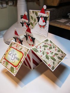 four christmas cards with santa hats and holly berries on them, sitting on a table