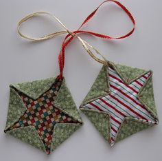 two ornament shaped like stars hanging from a red ribbon on a white surface