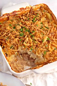 a casserole dish with meat and vegetables in it on a white table cloth