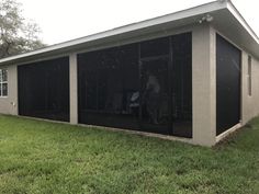 a woman sitting in the back of a house on top of a green grass covered yard