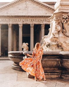 a woman in an orange dress sitting on a fountain