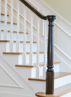 a white staircase with wooden handrail and banister