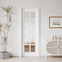 an empty room with a white cabinet and potted plant