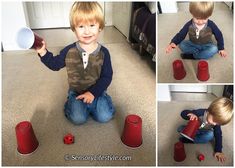 a little boy sitting on the floor playing with some red plastic cups and saucers