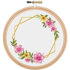 a cross stitch hoop with pink and yellow flowers on it, in front of a white background