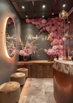 the interior of a beauty salon with flowers on the wall and stools in front