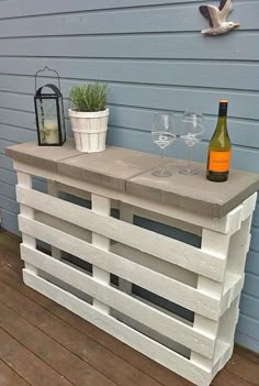 an outdoor bar made out of pallets and wine glasses on the side of a house