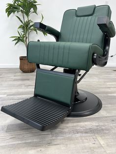 a green reclining chair sitting on top of a wooden floor next to a potted plant