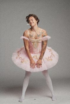 a man in a pink tutu and white tights with tattoos on his arm