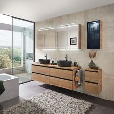 a bathroom with two sinks and a bathtub next to a large window overlooking the outdoors