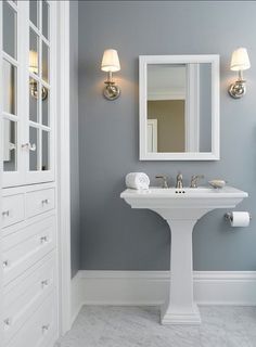 a white pedestal sink sitting under a bathroom mirror next to a wall mounted light fixture